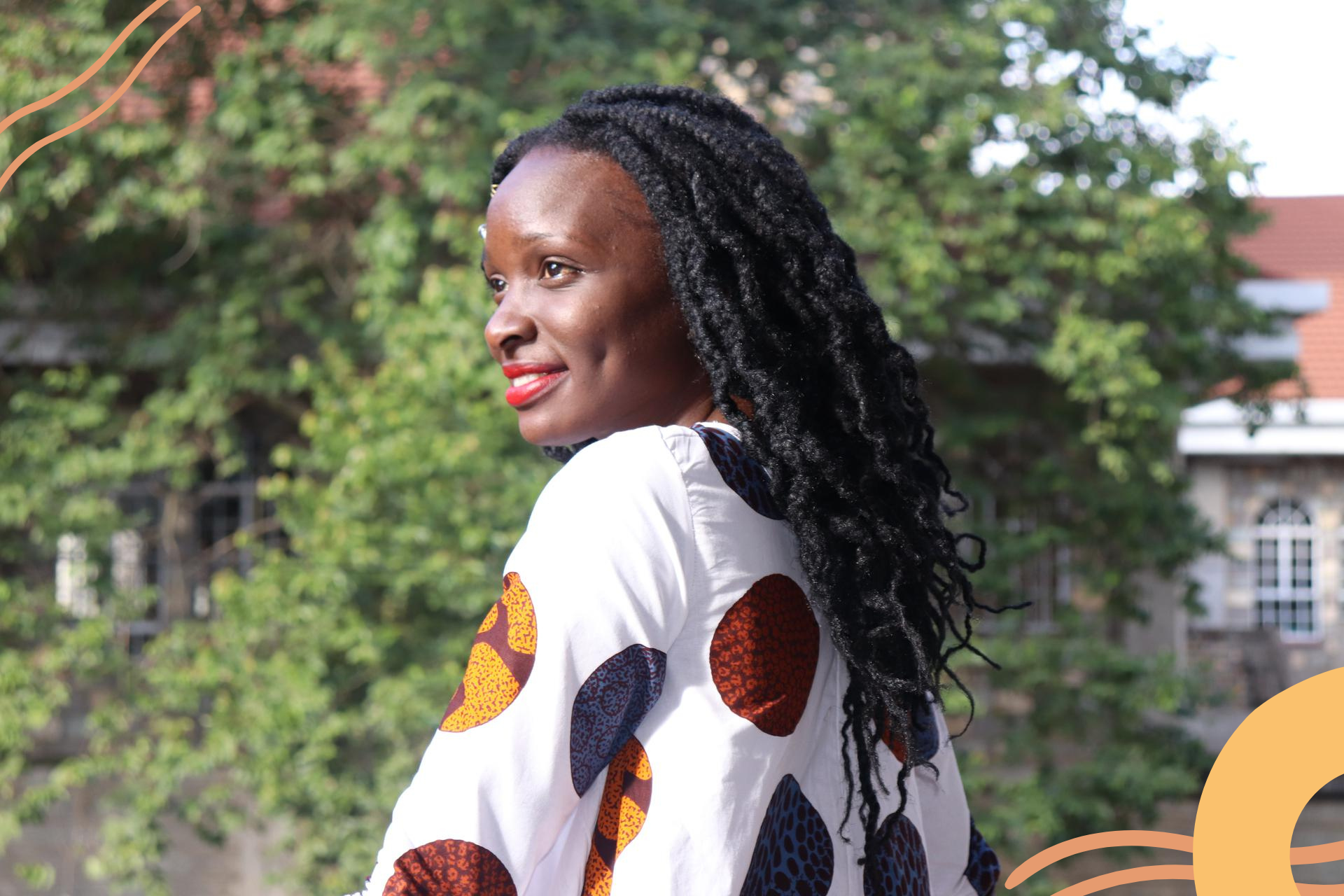 Image of a black woman wearing red lipstick, she smiles off camera and the sun hits her face.