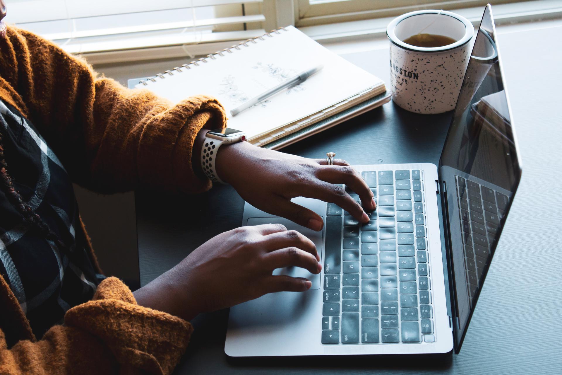 Image of woman with black hands using keyboard on mac computer